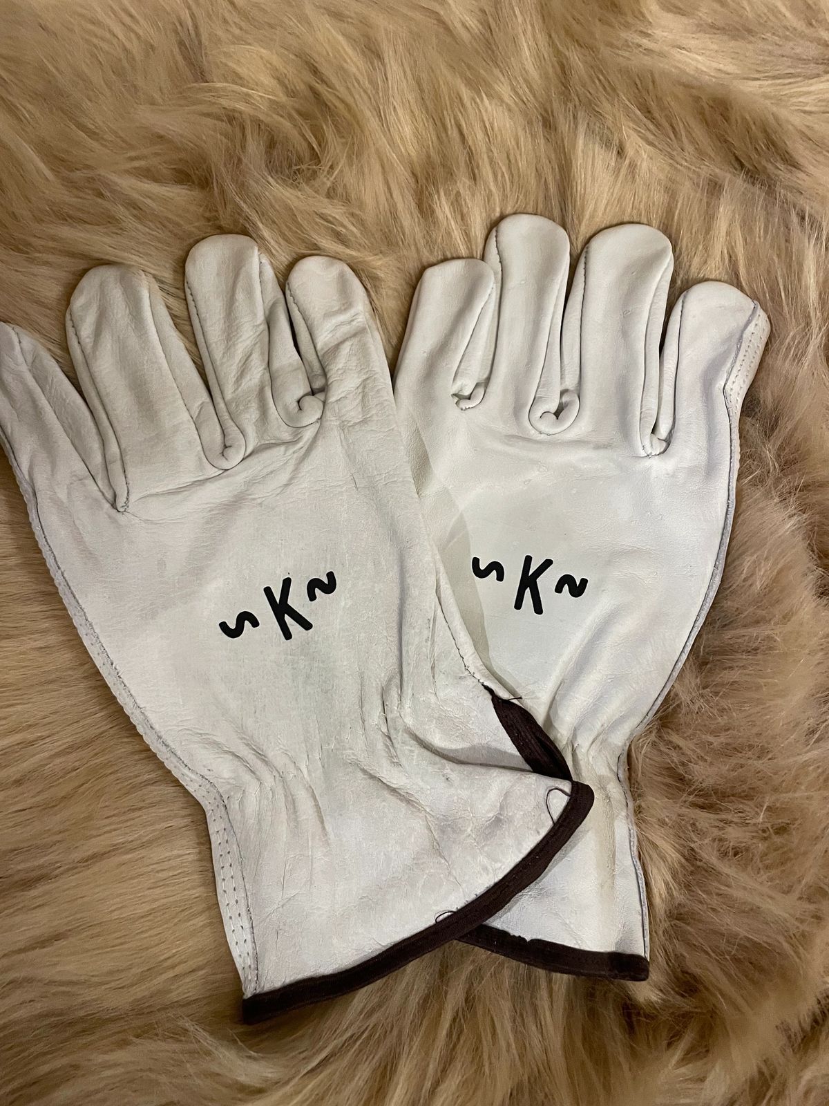 White gloves with black initials on fur.