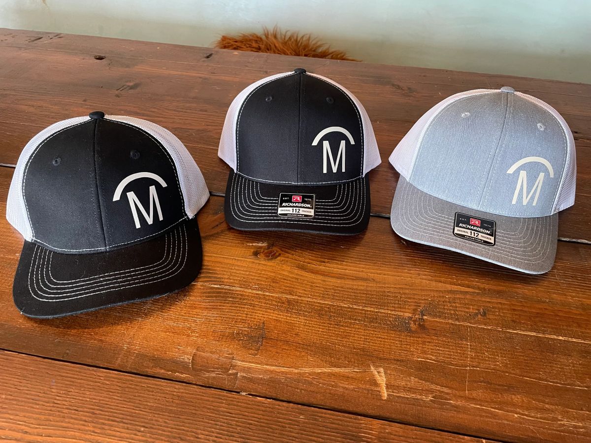 Three baseball caps on a wooden table.