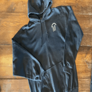 Black hoodie with white logo on wooden surface.