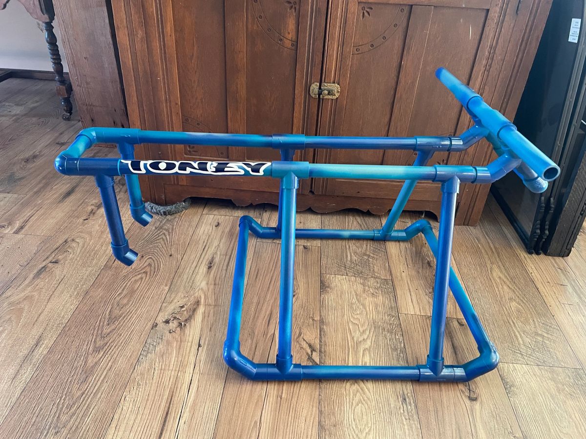 Blue PVC pipe bike frame on floor.