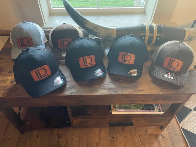 Six logo caps displayed on wooden table.